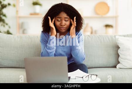 Tired african american lady touching and massaging temples Stock Photo