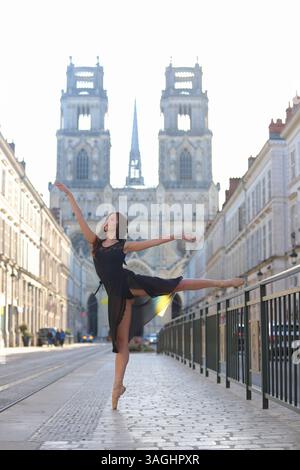 Ballerina performs arabesque on city street Stock Photo
