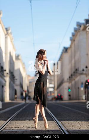 Ballet dancer on pointe in sunlit street Stock Photo