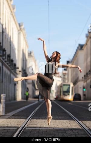 Ballerina dancing on tram tracks in city Stock Photo
