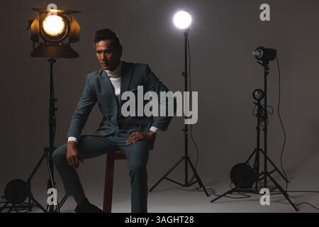 Confident man in stylish suit posing under studio lights, exuding elegance. Fashion, confidence, menswear, professional Stock Photo