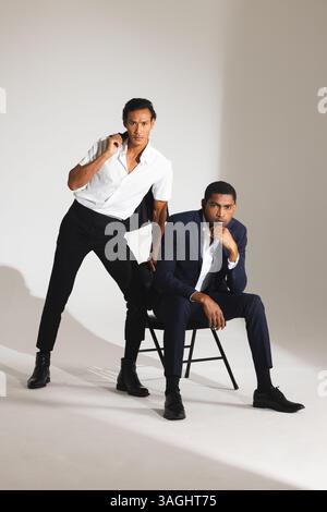 Confident men in stylish suits posing in modern fashion studio setting. style, menswear, confidence, elegance, business, tailoring Stock Photo