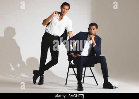 Confident men in stylish suits posing in modern fashion studio. menswear, style, elegance, sophistication, formal, clothing Stock Photo