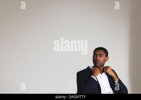 Confident man in suit adjusting collar, preparing for business meeting. professional, formal, corporate, executive, preparation, confidence Stock Photo