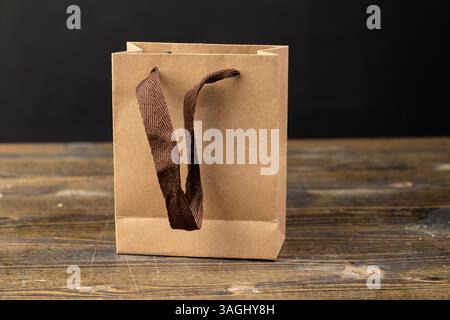 brown paper gift wrapping bag, made from recycled paper, small gift bag with brown satin ribbon handles, side view Stock Photo