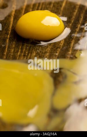broken cracked chicken egg spreads on a black wooden board, side view Stock Photo