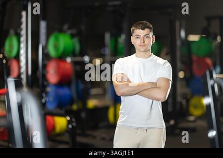 Athletic young man standing in gym with arms crossed Stock Photo