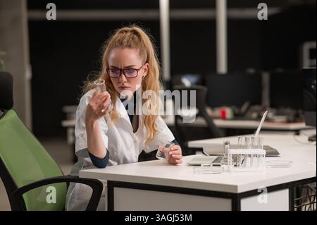 Caucasian woman in a medical gown doing laboratory experiments.  Stock Photo