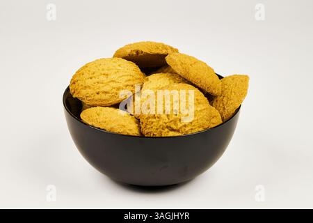 A plate of cookies sits on a white background. The cookies are small and round, and all the same color. The plate is black, and the cookies are arrang Stock Photo