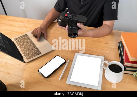 Young professional photographer busy editing photos on laptop computer from home studio. Young bearded photographer editing photos at home. Photojourn Stock Photo