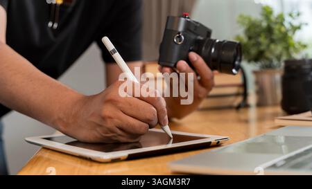 Close up of artistic hand using digital tablet and stylus while retouching image design at professional studio office desk. Woman doing editing work o Stock Photo