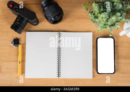 Desk of photographer with smartphone, cameras. Designer daily supplies shot knolling style. Vintage camera with blank spiral notebook and pen. Stock Photo