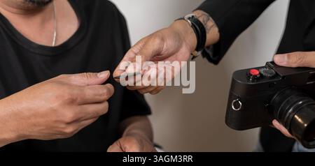 Male photographer ready to insert memory card to his professional DSLR camera while working in home office. Photographers at their studio. Mature prof Stock Photo