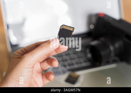 SD Card with camera. Inserting high-capacity memory card into photo camera outdoors. Photographer's hand holding memory card for preparing his camera Stock Photo