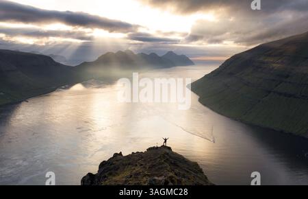 Silhouette of man over dramatic sunset with mountain and ocean in Faroe islands near Klaksvik Stock Photo