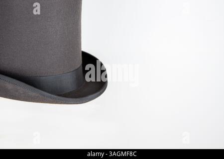 Magic hat. Topper. Elegant vintage gray beige wool felt top hat with black band on the wooden hat block. Grosgrain ribbon trim around rolled brim. Iso Stock Photo