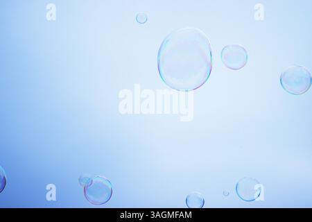 Large multicolored soap bubbles flying in the cloudy sky. Big bubble outdoors in the spring or summer street. Many bubbles isolated on white backgroun Stock Photo