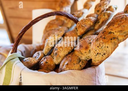 Bread in a basket in the wooden house interior. Assorted baking in a metal basket. Place for recipe and text. Background with rolling pin and flour. R Stock Photo
