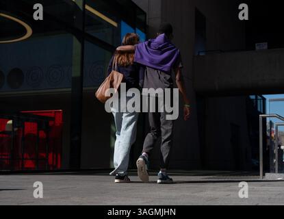 A young couple walk with arms around one another in Dublin city, Ireland. Stock Photo