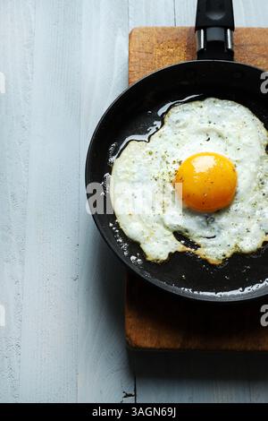 A single fried egg in a frying pan on a gray background. Healthy food concept. Directly above. Stock Photo