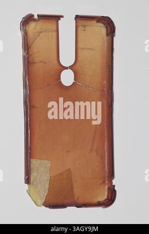 Damaged and discolored phone case, possibly burnt or aged, with visible cracks and peeling edges. Set against a white background, suitable for themes Stock Photo