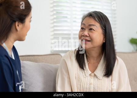 Caregiver and Patient Interaction. A caregiver and a senior woman engaging in a warm conversation during a home visit. Stock Photo