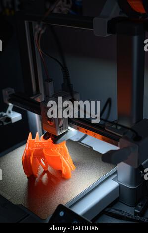 3D Printer Creating Orange Plastic Object on Platform Stock Photo