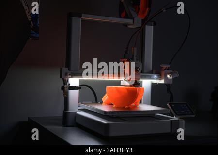 3D Printer Creating Orange Plastic Object on Platform Stock Photo