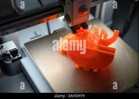 3D Printer Creating Orange Plastic Object on Platform Stock Photo