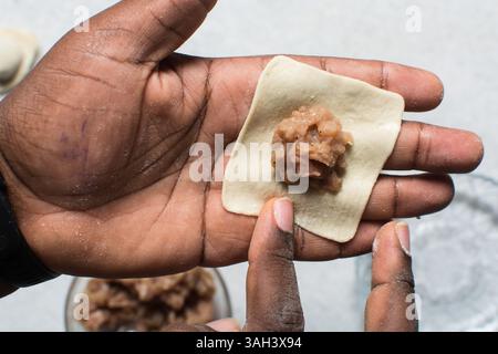 Overhead view of dumpling being wrapped, top view of wonton being filled, process of making homemade wontons Stock Photo