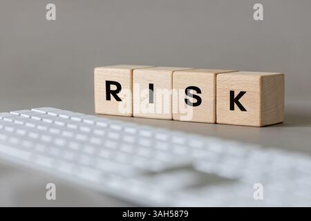 word Risk on wooden blocks and computer keyboard. Gray background. Concept, online safety. Inappropriate content. Online fraud Stock Photo