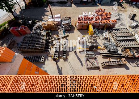 New wall made of ceramic blocks high above arranged improvised warehouse at open on the construction site,  pile of red blocks packed in plastic foil, Stock Photo