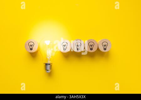 Glowing light bulb and light bulb icons on round wooden blocks. Beautiful yellow background. Concept of ingenuity, technological development, Future i Stock Photo