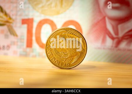 New Zealand one dollar coin on a $100 banknote background. Financial concept Stock Photo