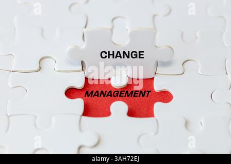 Change management of the sign. White puzzle pieces reveal change management symbol on red background. business transformation and organizational chang Stock Photo