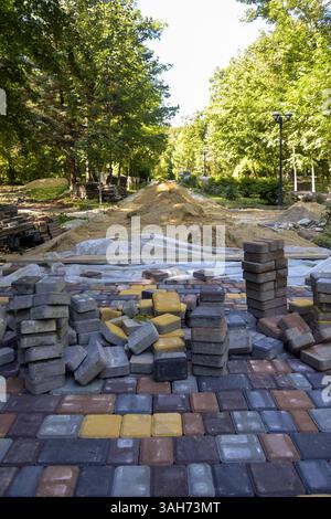 Process of laying multi-colored paving slabs on park alley on warm summer sunny day fills atmosphere with life and joy. Close-up. Copy space for text. Stock Photo