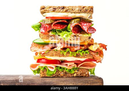 Layered mega sandwich with ham, bacon, salami, cheese and fresh vegetables isolated on white background, copy space.  Healthy food design, lunch sandw Stock Photo