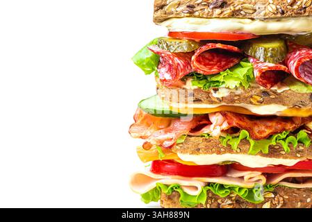 Layered mega sandwich with ham, bacon, salami, cheese and fresh vegetables isolated on white background, extremely close up. Detailed healthy food des Stock Photo