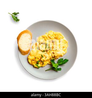 Scrambled Eggs for breakfast isolated on white background, top view. Keto food, healthy breakfast with scrambled egg and slice of bread on plate. Stock Photo