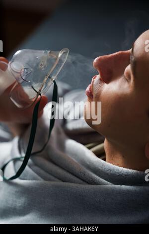 Using compressor nebulizer for disease treatment at home. Man inhaling through oxygen mask for cough treatment Stock Photo