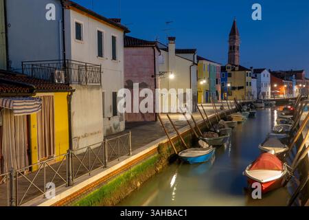 Night view of small boats docked in the canal, in a beautiful street with picturesque houses in Burano, an idyllic island in Venice, Italy. Stock Photo