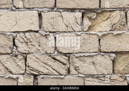 Close-up photo of a natural shell rock stone brick wall showcasing its rustic rough texture and earthly tones. Suitable background for architectural, Stock Photo