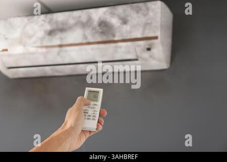 Man using air conditioner covered with mildew Stock Photo
