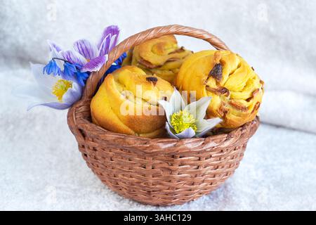 Small Easter cakes in a basket with flowers on a light background. Selective focus Stock Photo