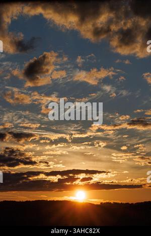 A mesmerizing canvas of clouds unfolds across the Galician sky as the sun sets. Layers of wispy and dense clouds dance in golden and blue tones, creat Stock Photo