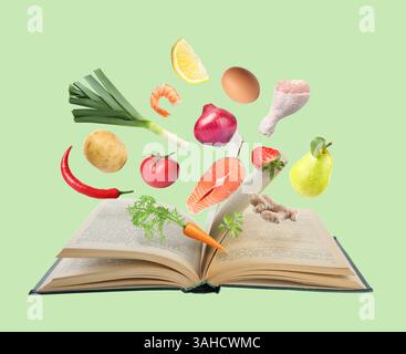 Fresh ingredients in air over recipe book on light green background Stock Photo