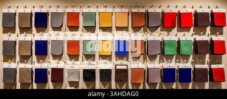 Catalog of multi-colored fabric samples hanging on the wall, textile industry background Stock Photo
