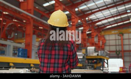 Back professional heavy Industry engineer woman worker wearing safety helmet using clipboard to Stock Photo