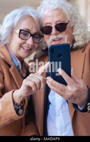 Happy senior couple using smartphone together, smiling and enjoying technology. Stock Photo