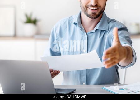 Job Interview. Friendly male HR manager extending hand for handshake at camera Stock Photo